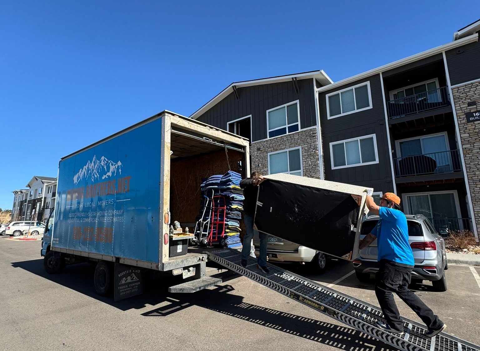 Movers carrying household furniture from a Denver home to a moving truck